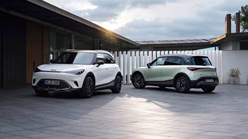 Two smart electric vehicles parked outside a contemporary building with a cloudy sky overhead